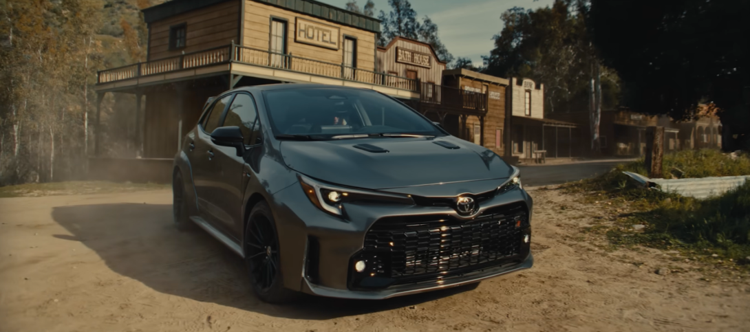 Grey Toyota Corolla stands near the wooden hotel